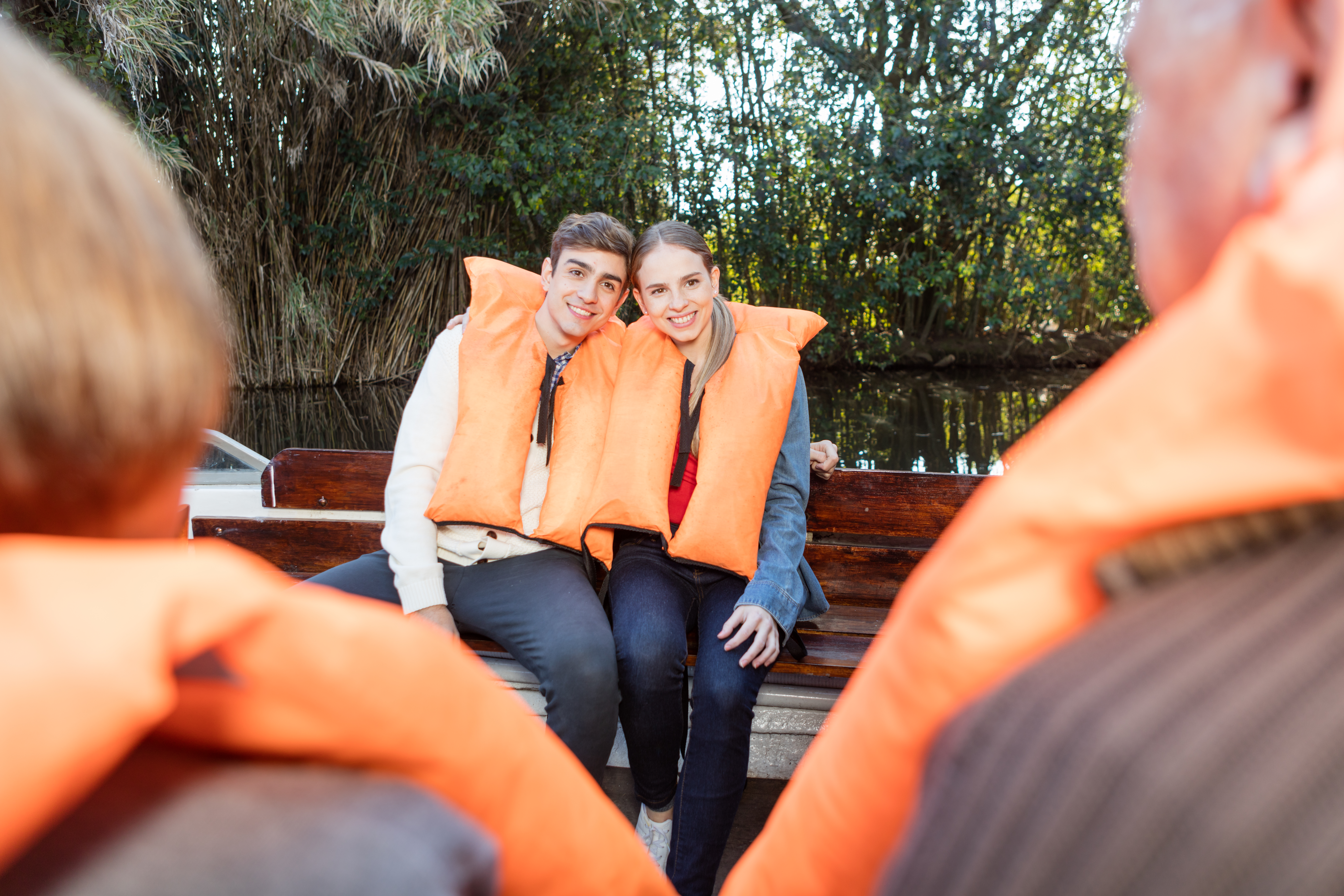 Usmiaty pár v oranžových vestách sedí spolu na člne.