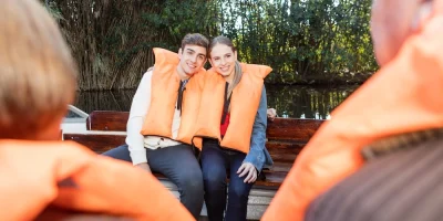 Usmiaty pár v oranžových vestách sedí spolu na člne.